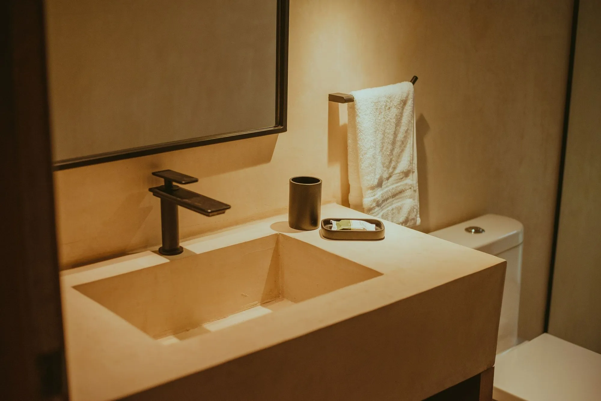 A lime-plaster basin and counter in warm lamplight