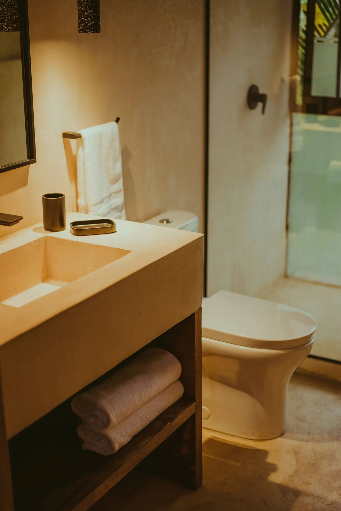 A lime-plaster counter and basin with towels on the shelf below