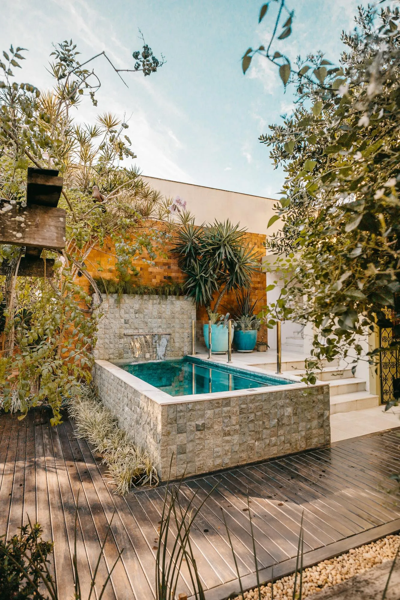 A small stone-edged cold plunge on a timber deck among plants