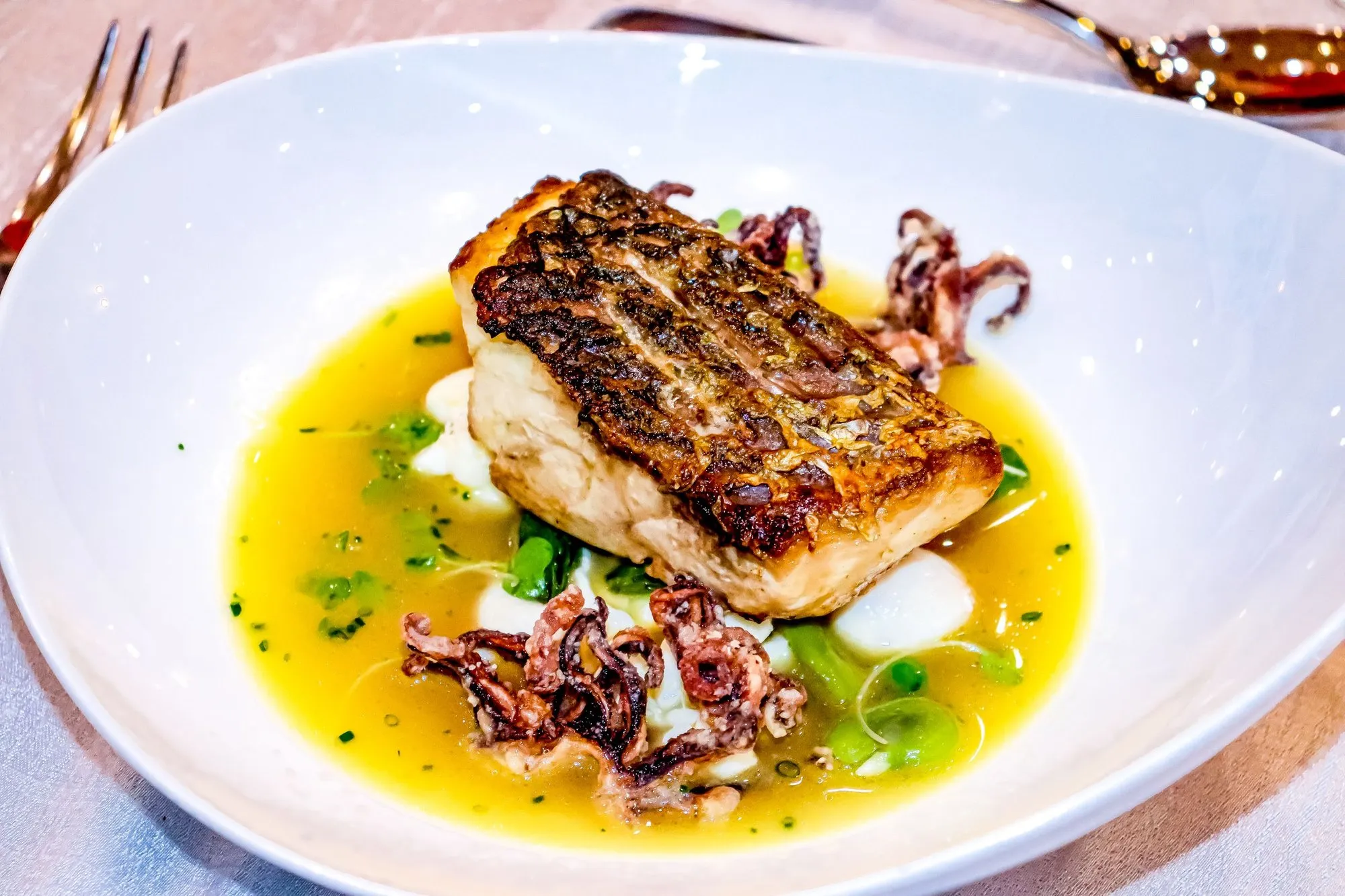 Seared hake with squid in a saffron broth