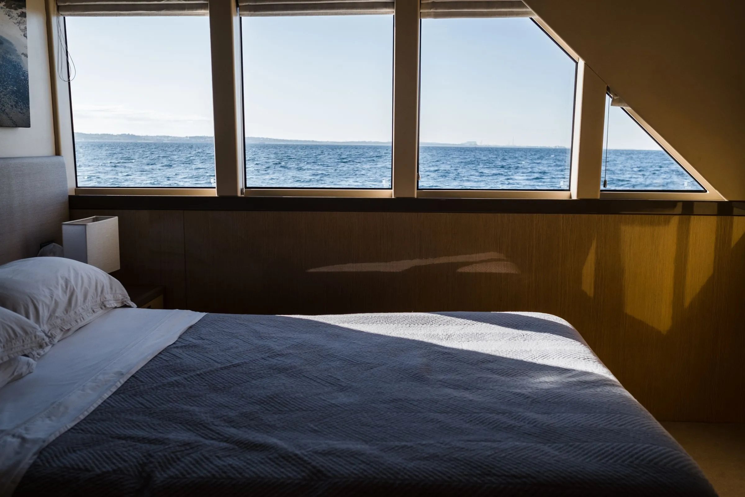 A bedroom at Merecombe, the bed facing a row of windows full of open sea