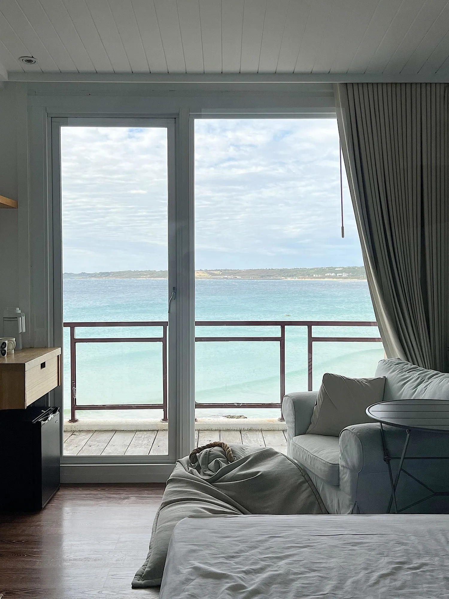 The Cove Suite, with a glazed door open onto a small balcony and the bay beyond