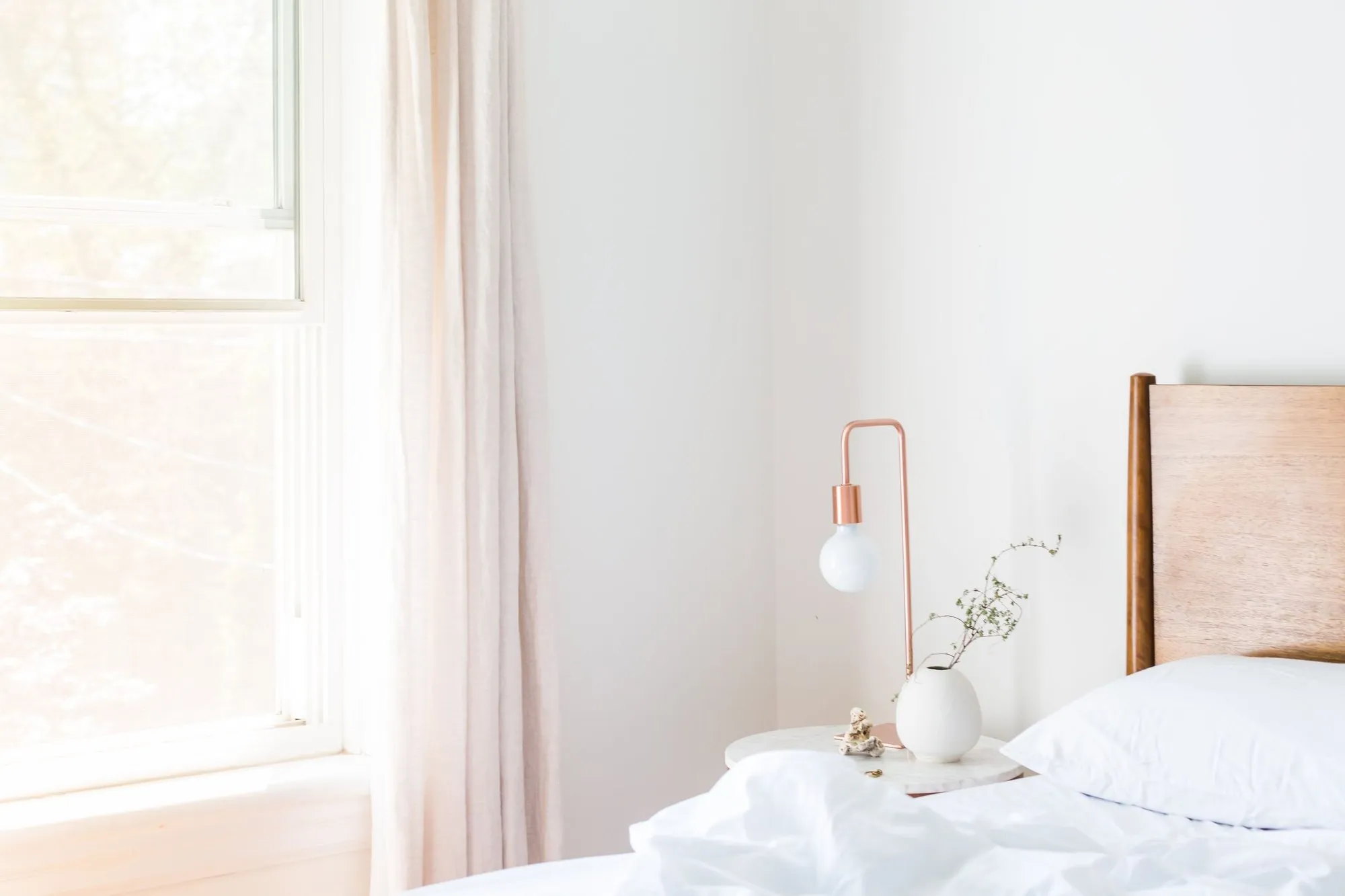 The Garden Room, a timber headboard and white linen in soft garden light